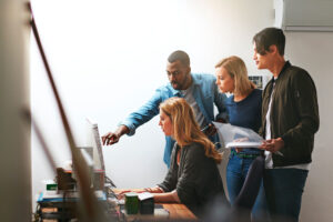 Collaboration entre professionnels autour d'un ordinateur, symbolisant le travail en équipe pour la conception de sites internet sur mesure.